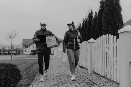 Free Two couriers delivering packages in a residential neighborhood. Stock Photo