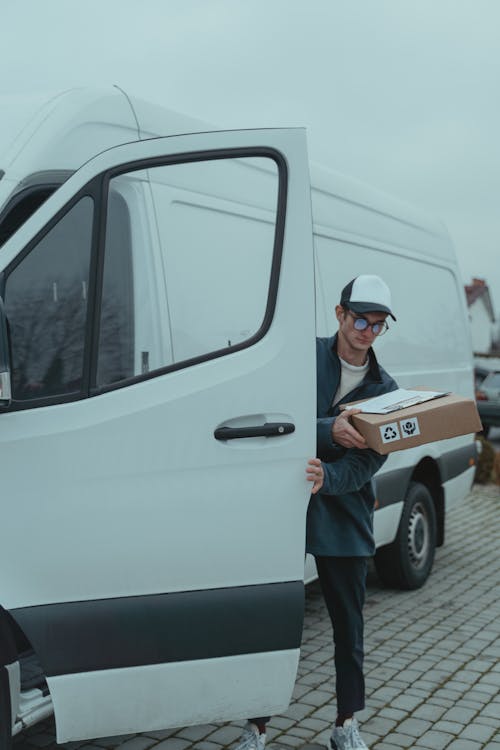 Man in Blue T-shirt Standing Beside White Van