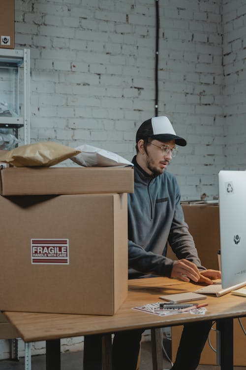 Employee using a Computer beside Carton Boxes 