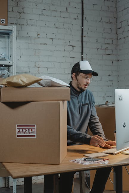 Employee using a Computer beside Carton Boxes
