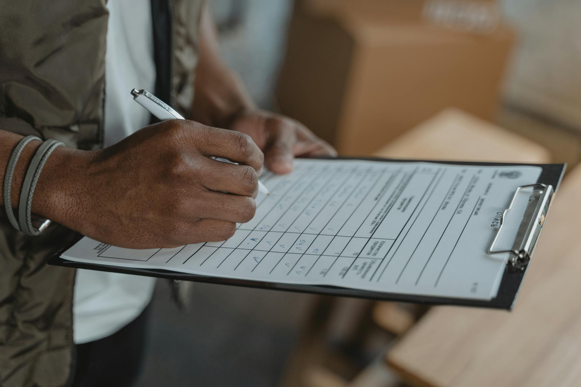 Close-up of person writing on form attached to clipboard, capturing the diligent process.