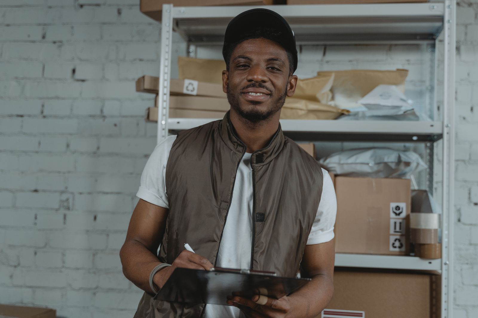 Warehouse employee holding a clipboard, surrounded by packages and smiling