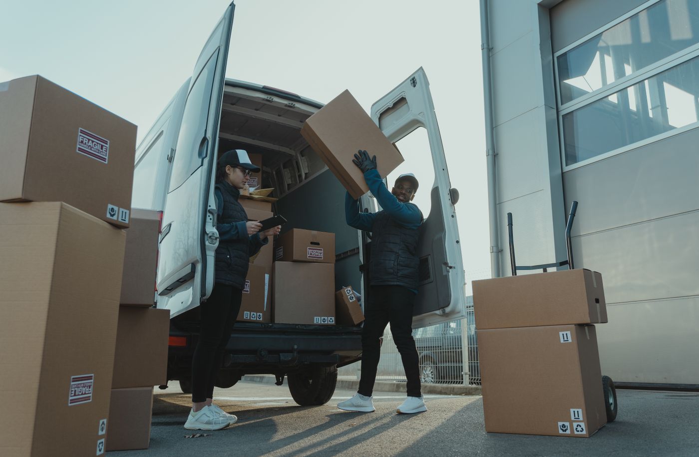Courier carrying shipping boxes beside a delivery vehicle