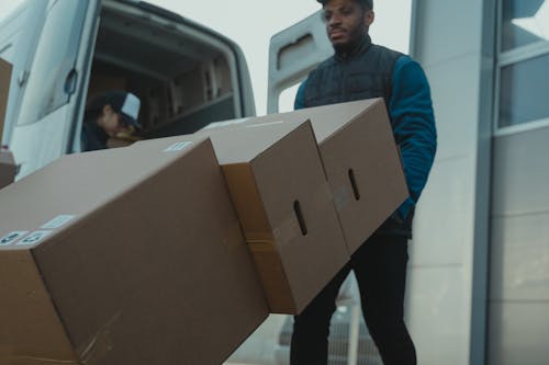 Free Delivery Man pushing a Trolley with Carton Boxes Stock Photo
