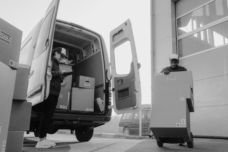 Delivery Man Pushing A Trolley With Carton Boxes