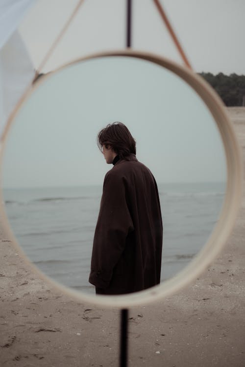 Free Stylish man model standing on sandy coast near sea Stock Photo