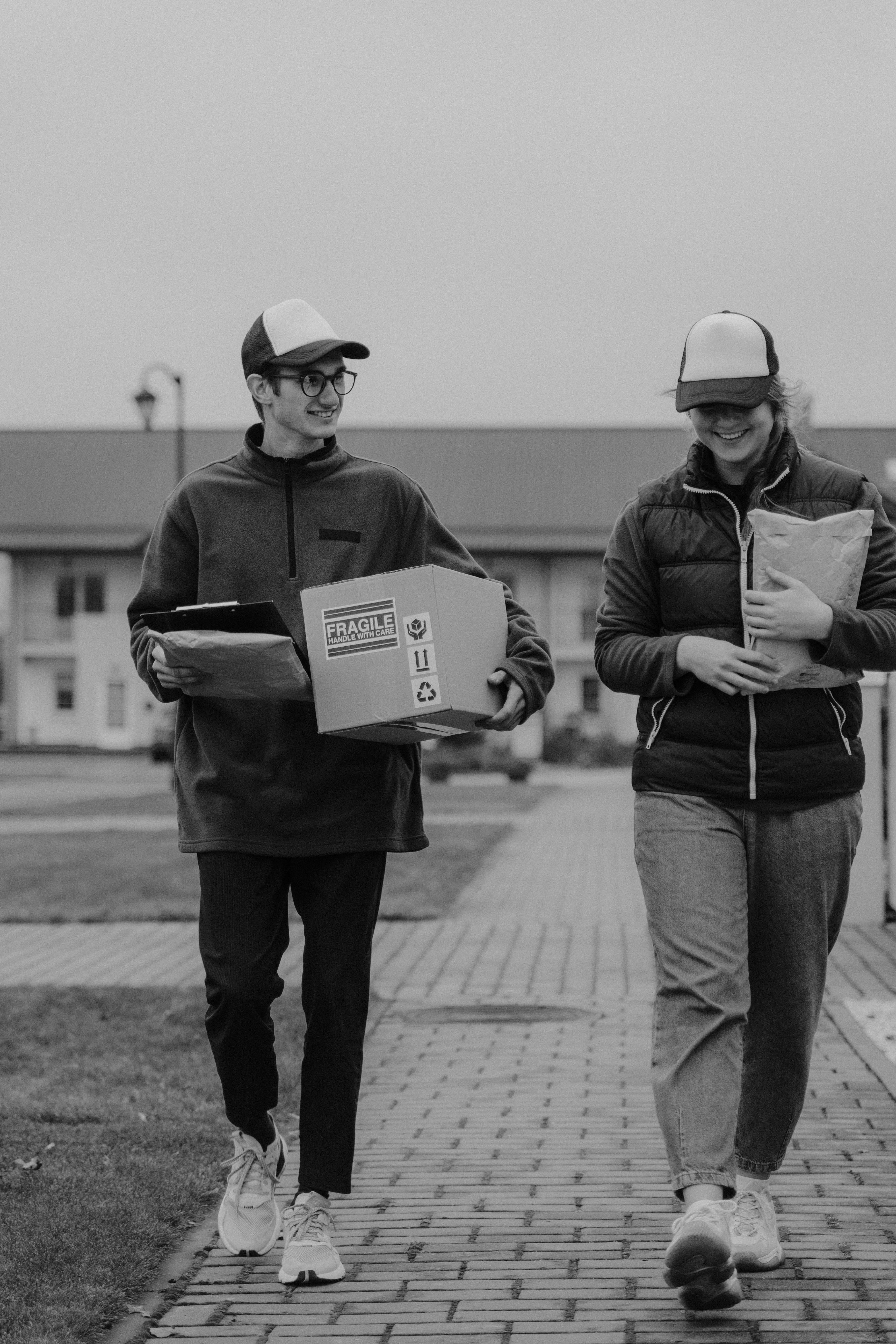 moncohrome photo of two delivery people walking alongside each other