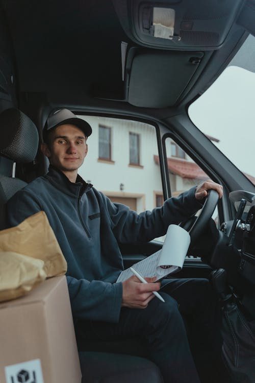 Free Delivery Man sitting on Driver's Seat  Stock Photo