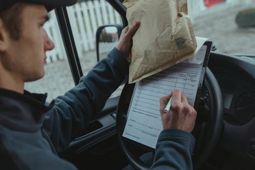 Person writing on a Paper on Top of a Steering Wheel 
