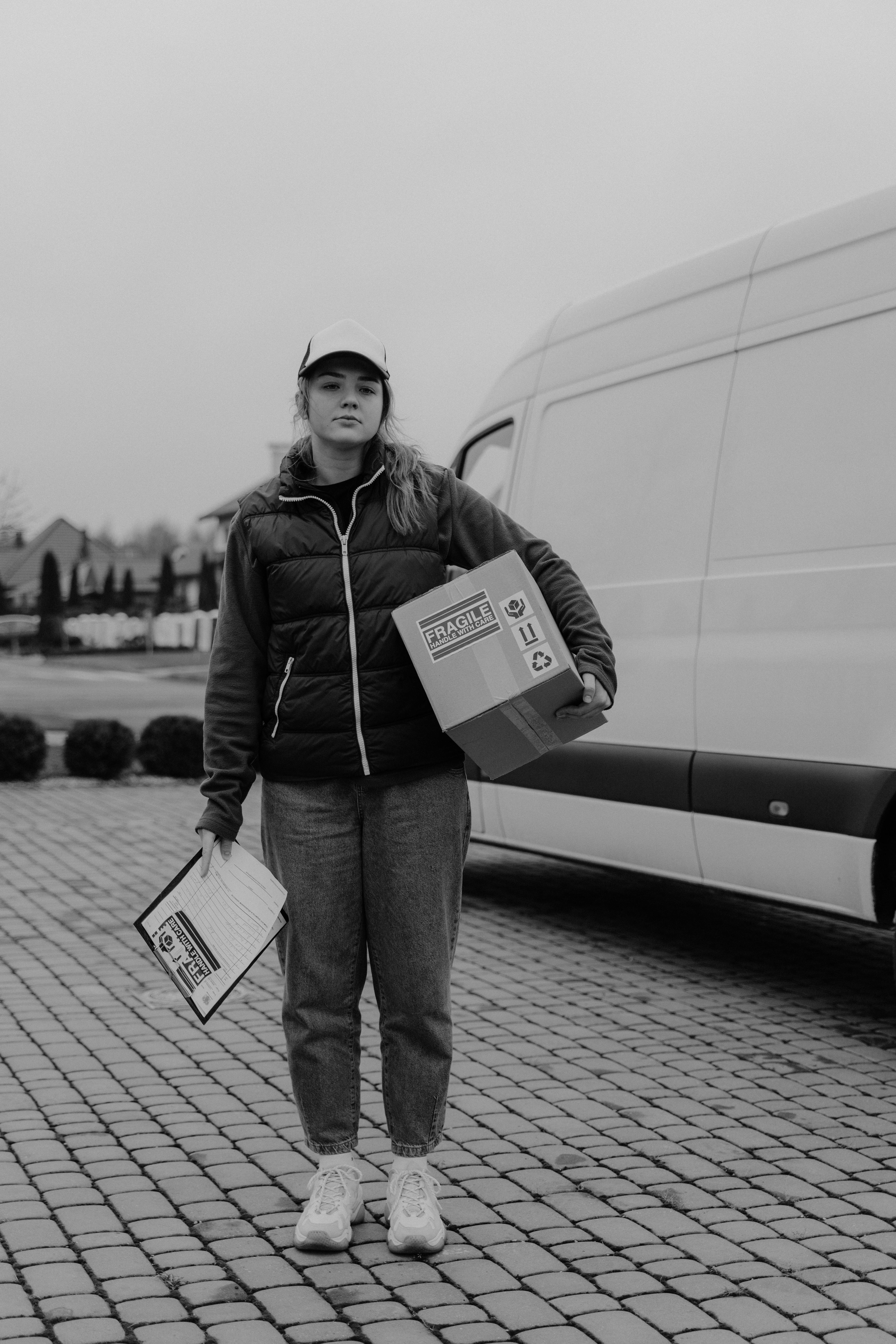 monochrome photo of female courier carrying a box