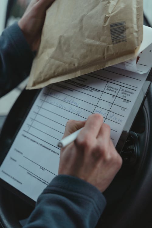 Person writing on a Paper on Top of a Steering Wheel 