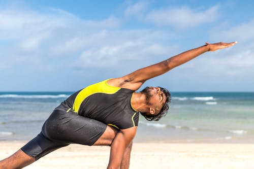 Free Man in Yellow and Black Tank Top Doing Exercise on Seashore at Daytime Stock Photo