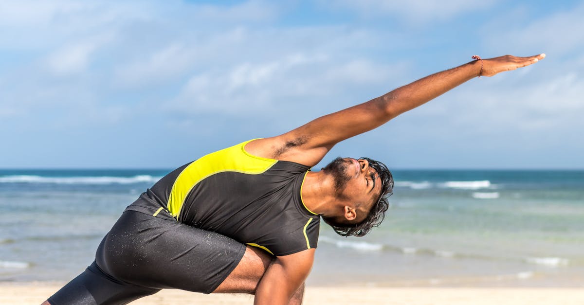 Man in Yellow and Black Tank Top Doing Exercise on Seashore at Daytime