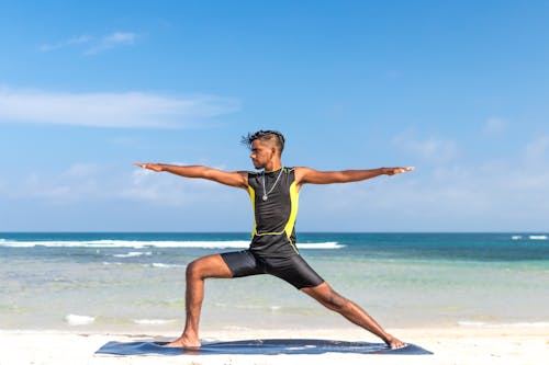 Free Man in Sleeveless Wet Suit Doing Some Aerobics at the Beach Stock Photo