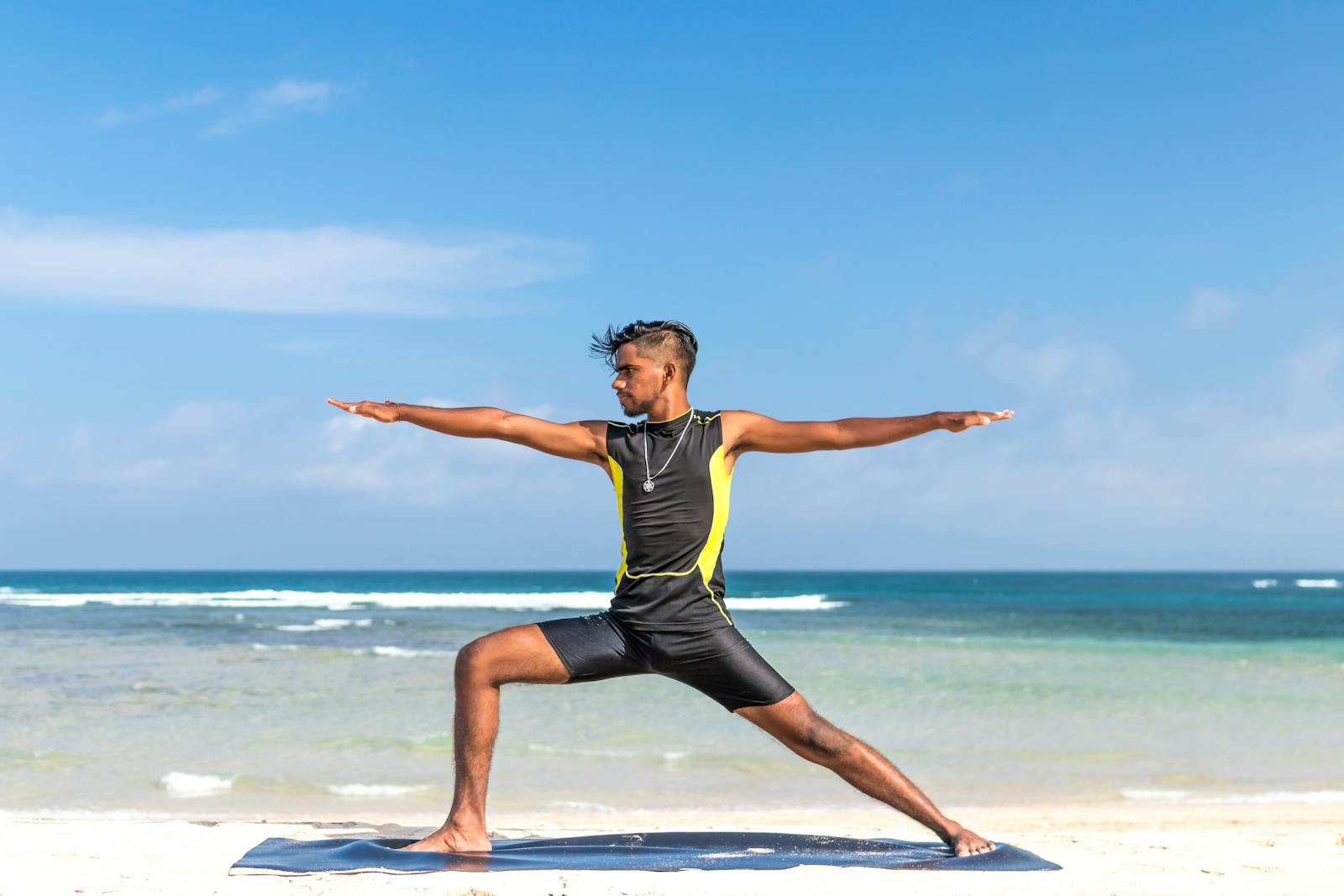 Man stretching on the beach in a wetsuit.