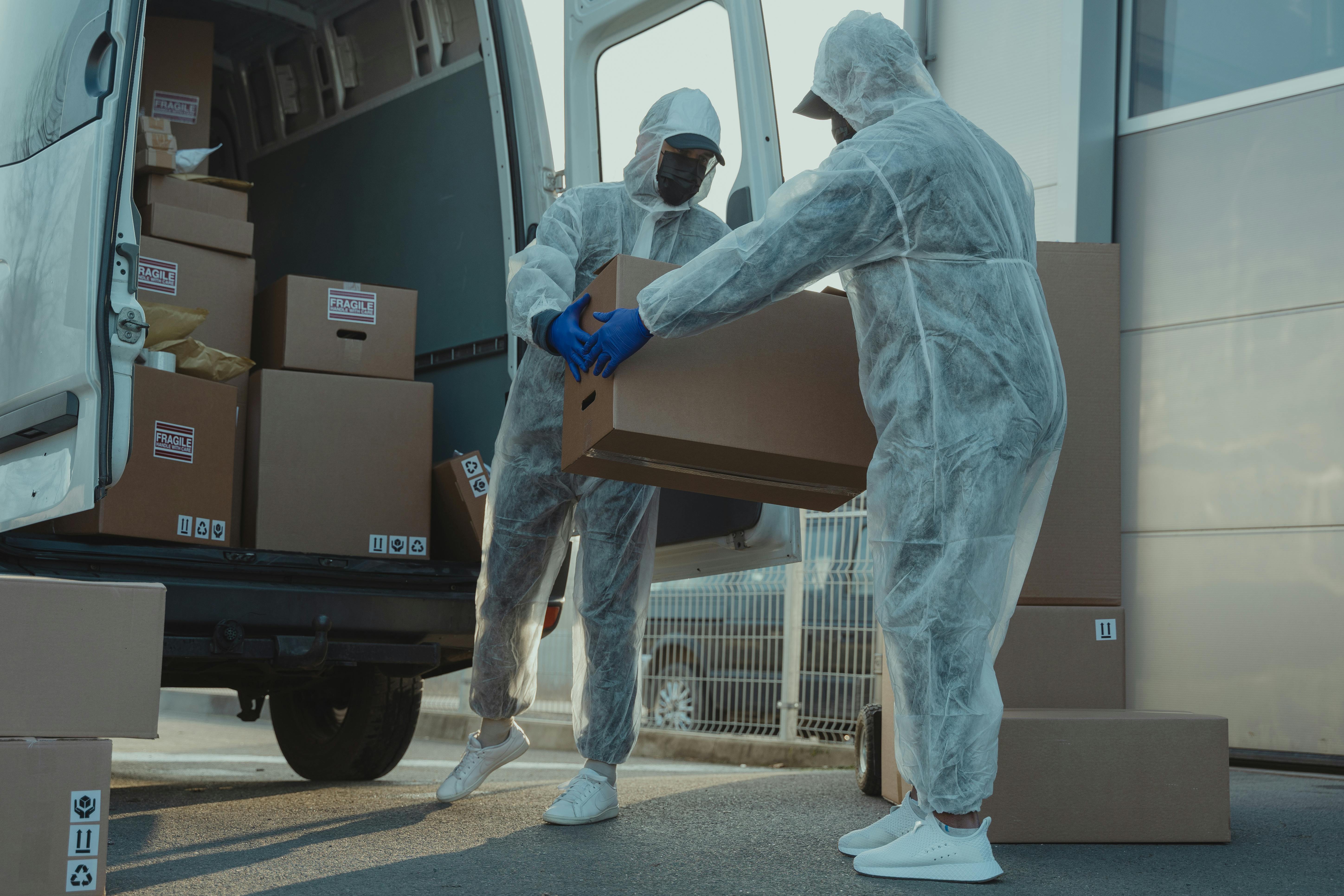 two delivery men in ppe carrying a box