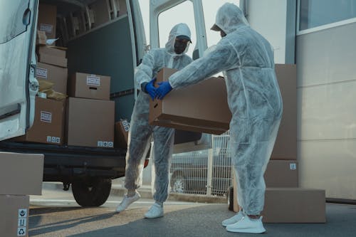 Two Delivery Men in PPE carrying a Box 