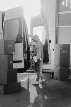 Courier in protective gear loading a delivery van with packages, monochrome style.