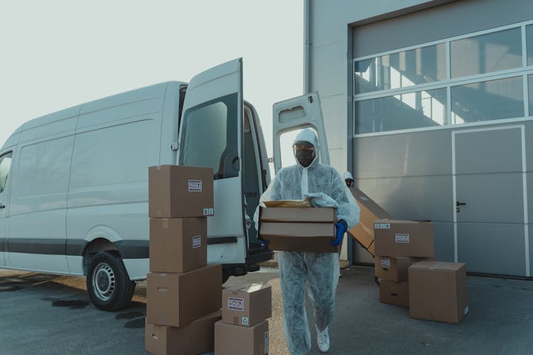 Delivery Man In PPE Carrying A Box