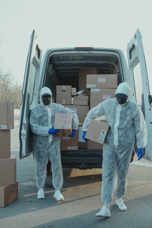 Two Delivery Men in PPE carrying a Box