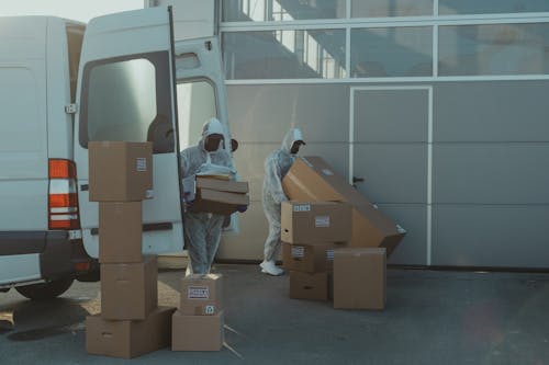 Two Delivery Men in PPE carrying a Box