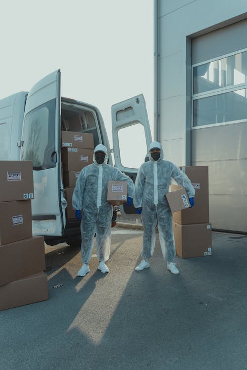 Free Delivery Men in PPE carrying a Box Stock Photo