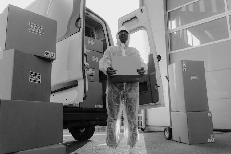 Delivery Man In PPE Carrying A Box