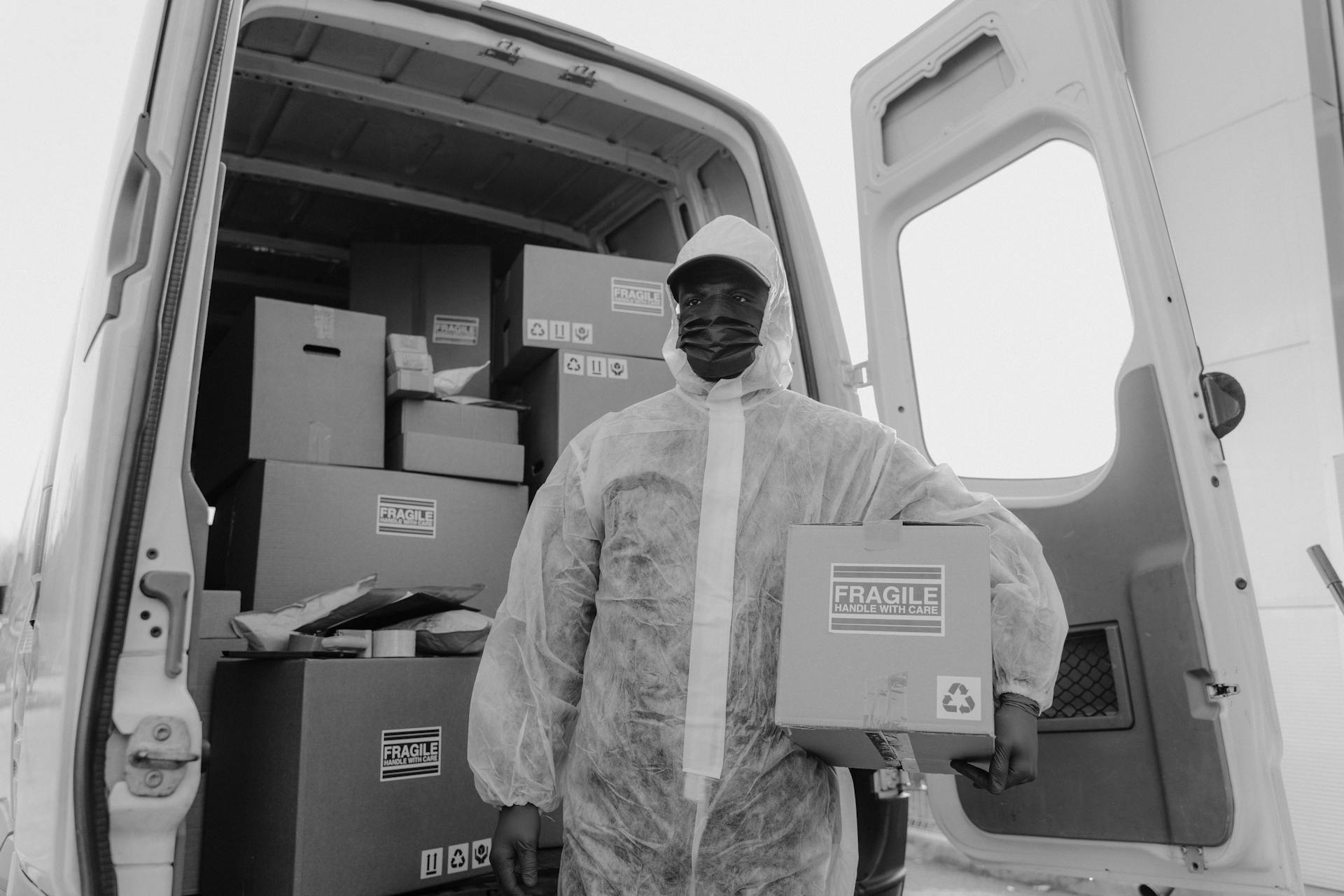 Courier in protective gear handling packaging in a delivery van, focusing on safe transport.