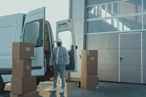 Delivery Man in PPE standing beside a Delivery Van 