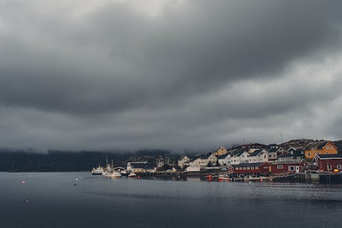 Body of Water Near City Buildings Under Gray Clouds