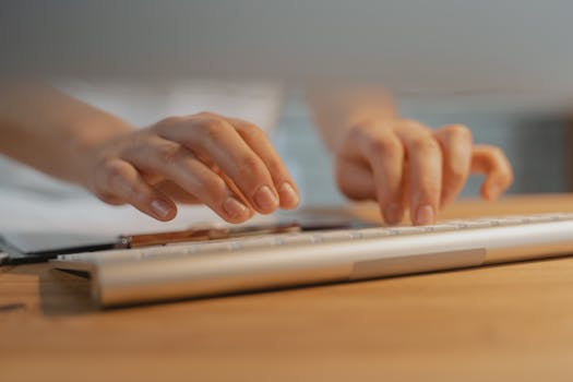 Close-up of hands typing on a white keyboard, showcasing modern technology and productivity.