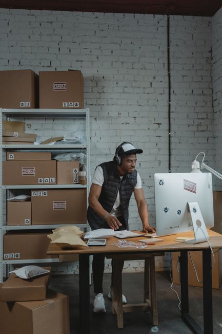 A man in a warehouse packaging orders for shipping. E-commerce and business concept. A man in a warehouse packaging orders for shipping. E-commerce and business concept.