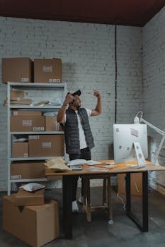 A lively man having fun and dancing in a warehouse room filled with boxes and packages.