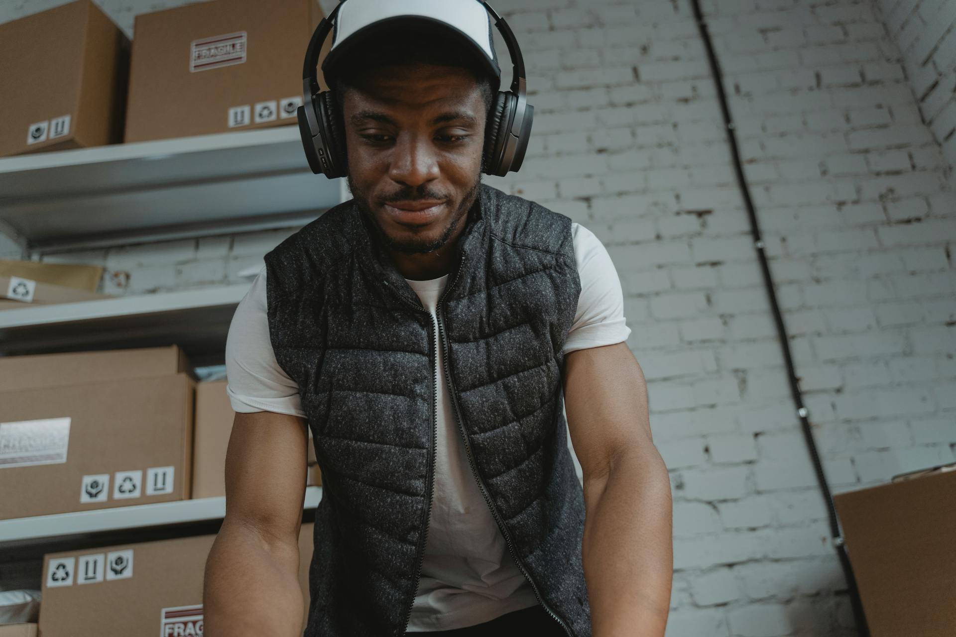 Focused warehouse employee wearing headphones while organizing packages indoors.