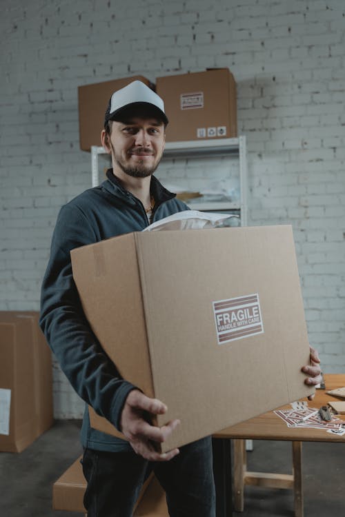 Man in Blue Long Sleeve Shirt Holding Brown Cardboard Box