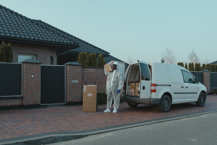 Delivery Man In PPE Carrying A Box 