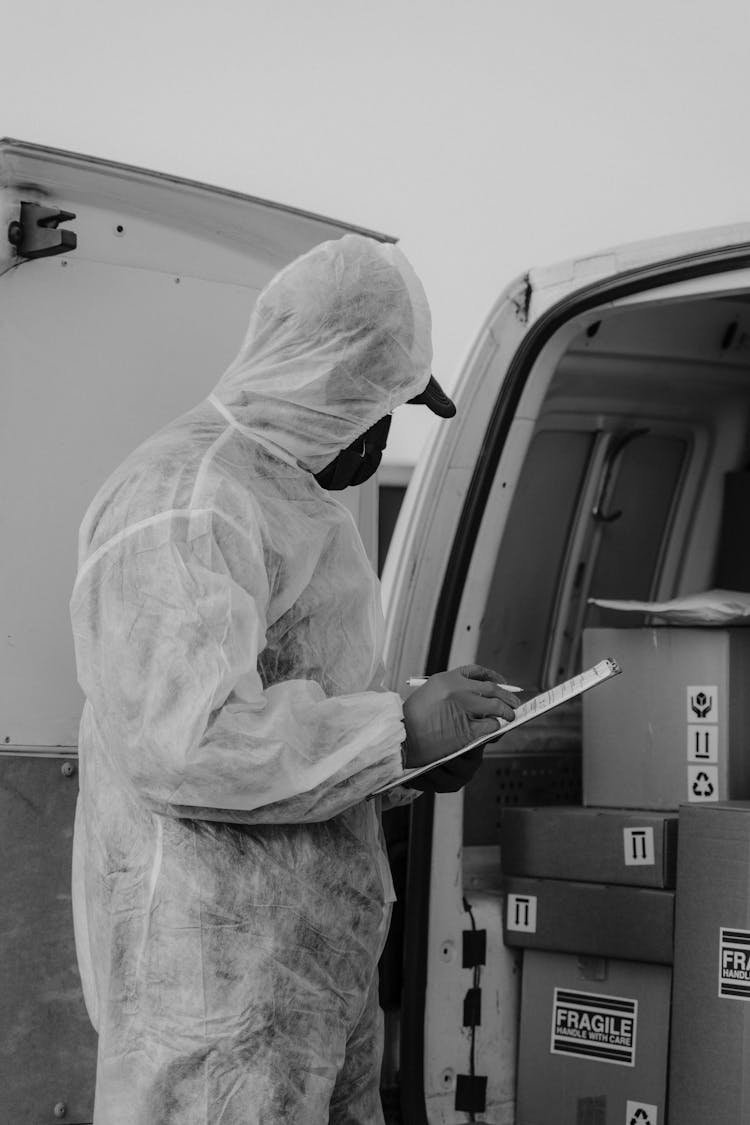 Delivery Man In PPE Writing On A Clipboard