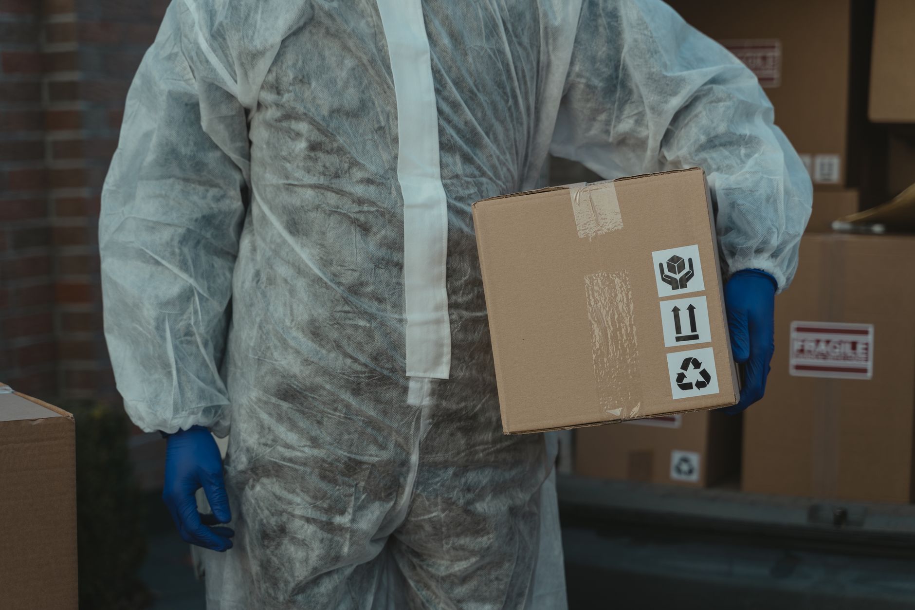 e-commerce warehouse worker wrapping a fragile product in bubble wrap beside stacked cardboard boxes and shipping labels