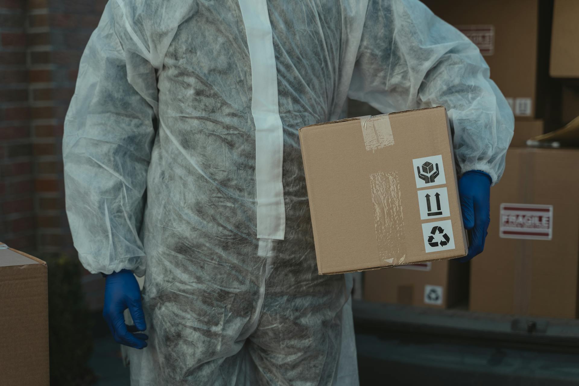 Person Wearing a Personal Protective Equipment Holding a Parcel