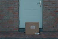 A Brown Cardboard Box Beside White Door
