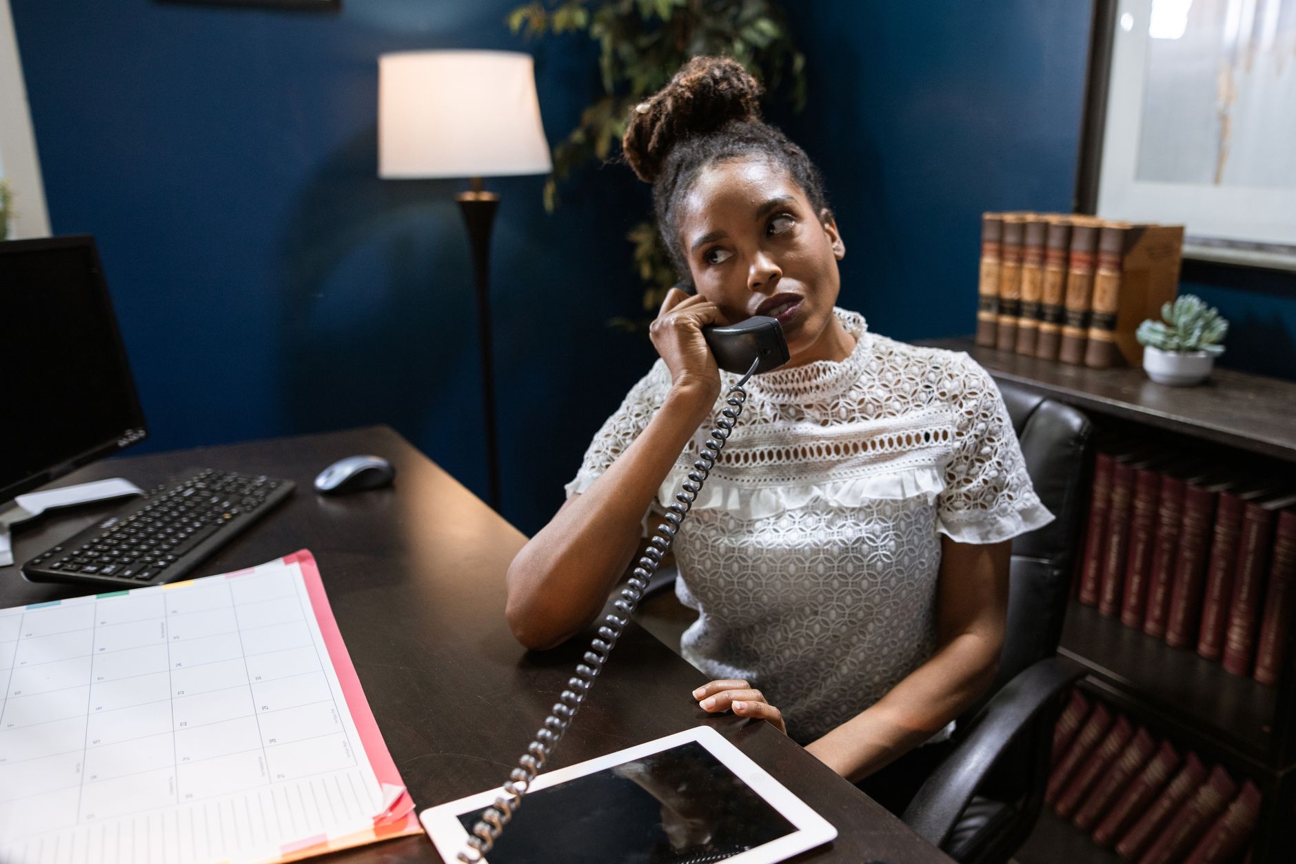 Small business owner comparing phone call bookings on a calendar next to a laptop, illustrating AI receptionist vs human receptionist costs