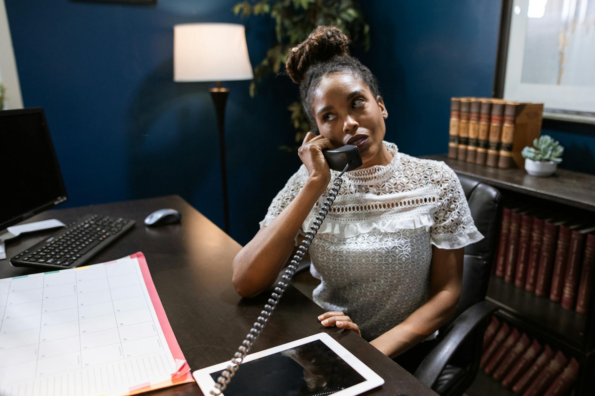 Businesswoman engaged in a phone call at an office desk, focused and working.