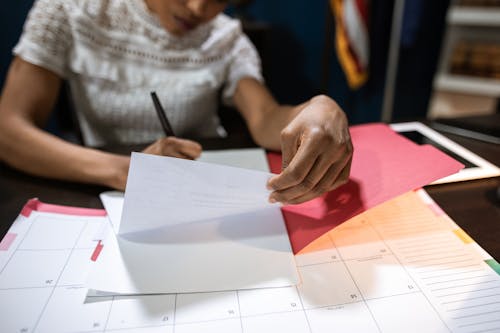 Donna In Camicia Grigia Che Scrive Su Carta Bianca