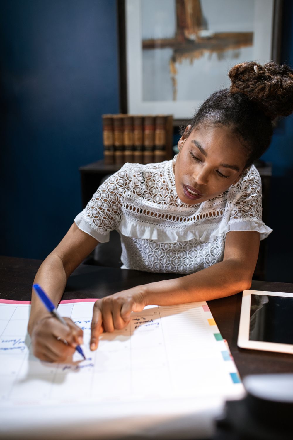 Professionnelle noire planifiant ses tâches sur un calendrier de bureau