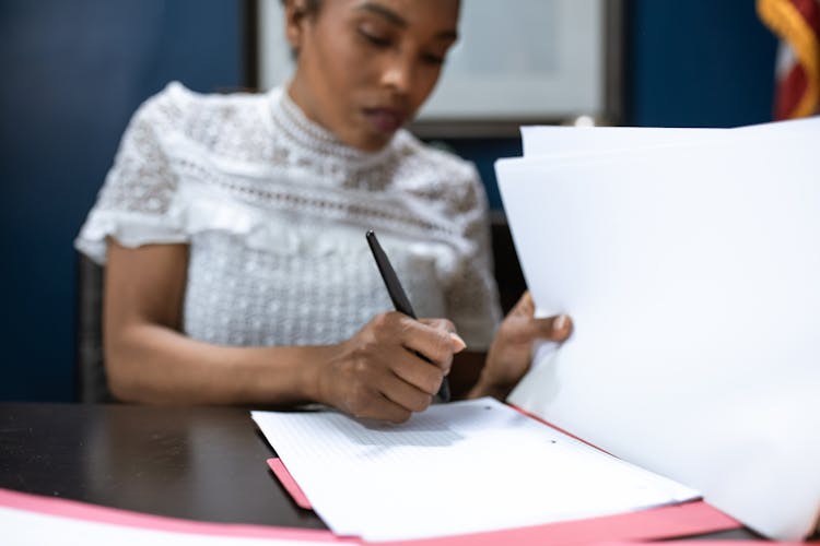 A Woman In Public Official Signing A Document