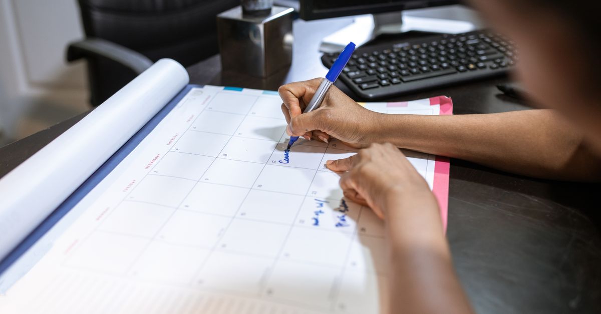 Profissional organizando agenda de atendimentos em calendário de mesa