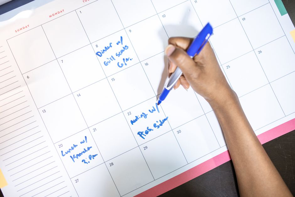 Person writing on a calendar or planner — clear your calendar for the ceremony day and 2–3 days of recovery; do not plan to return to demanding work immediately