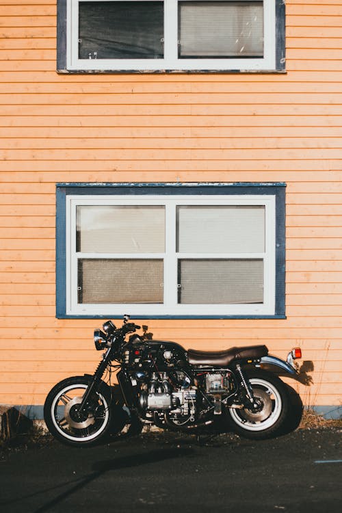 Free A Black Cruiser Motorcycle Parked Beside Brown Wooden Wall Stock Photo