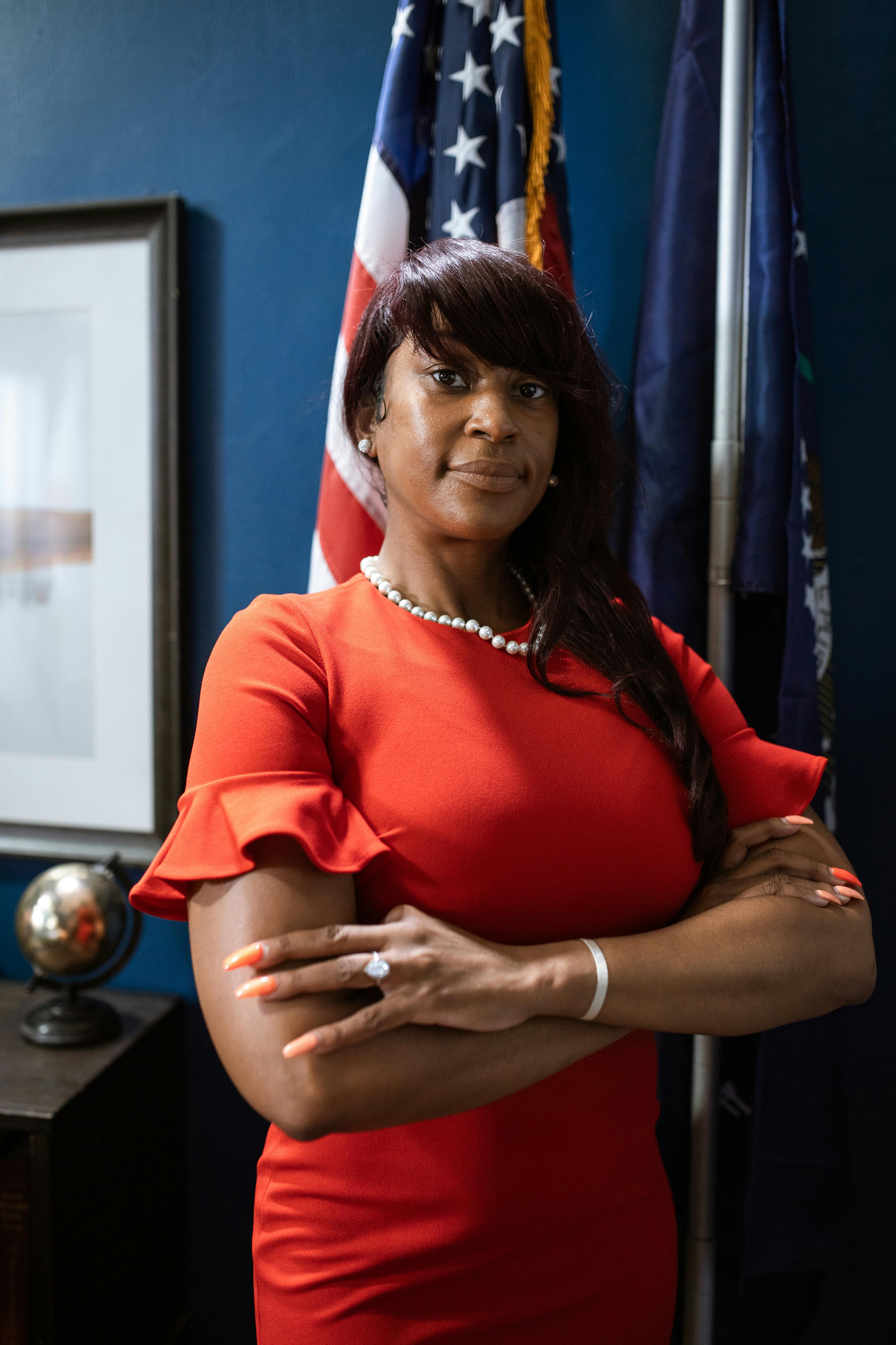 Portrait of a confident woman standing in an office with an American flag.
