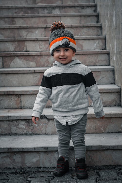 Boy in Gray Hoodie and Knit Hat Standing Near Concrete Stairs